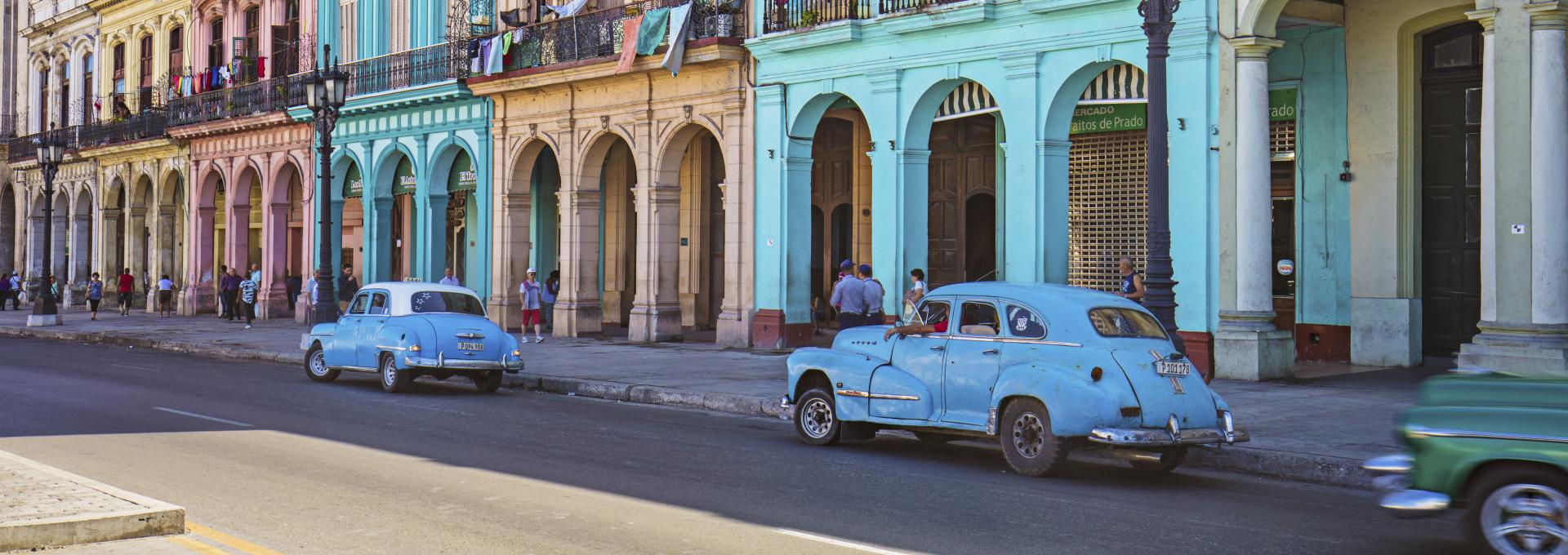 Vintage cars parked on roadside. Taxis on street in city. Vehicles against residential buildings.